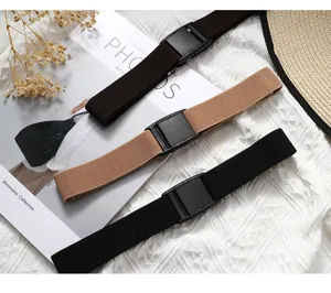 Detail shot of three elastic waist belts in dark brown, khaki, and black with plastic buckles.