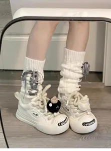 Weiße Strick-Beinwärmer und gestapelte Socken mit lässigen Plateau-Sneakern für Damen.