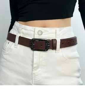 Detailed shot of retro brown debossed waist belt with ornate buckle, styled on denim.