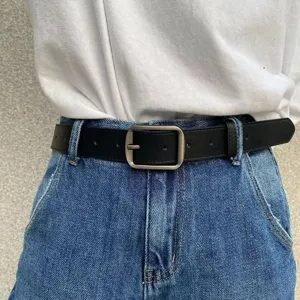Minimalist black leather belt for jeans with matte silver buckle, stylish waist accessory.