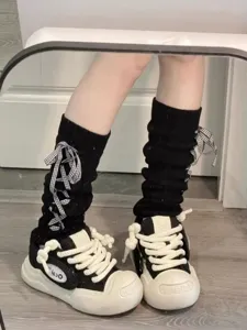 Schwarze Strick-Beinwärmer mit karierten Schleifen kombiniert mit chunky Freizeitschuhen für Damen.