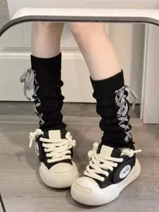 Damen Mode Strick Beinwärmer schwarze Stulpen mit Karobändern und klobigen Sneakers.