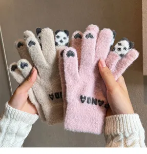 Close-up detail of cute winter knitted warm five-finger panda gloves in soft fuzzy texture.
