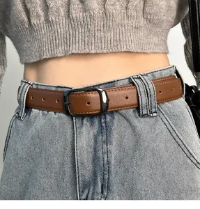 Close-up detail of brown leather belt with black metal buckle worn on blue jeans.