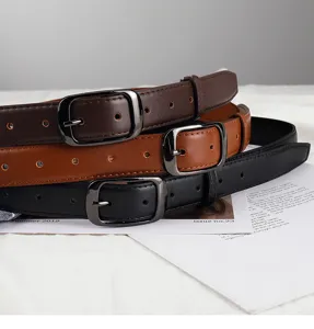 Detail view of minimalist thin leather women belts with metal pin buckle for casual jeans wear.