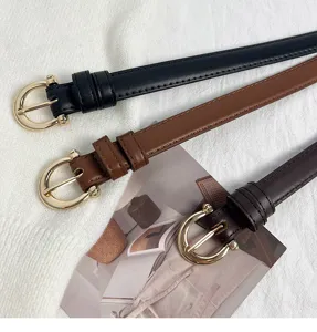 Primo piano dettagliato di cinture in pelle sottili con fibbie ad ardiglione oro e marrone.