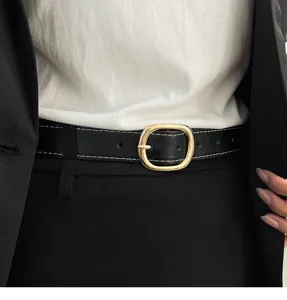 Close-up detail of a minimalist black leather belt with contrast white stitching and gold buckle.