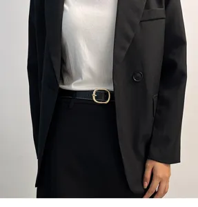 Detail shot of minimalist women black leather belt featuring elegant gold metal square buckle.
