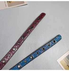 Detailaufnahme von stilvollen Glitzer-Ledergürteln mit Ösen und Nieten in Rosa und Blau.
