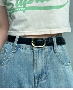 Women's black leather belt with gold oval buckle paired with classic blue denim jeans stylish accessory.