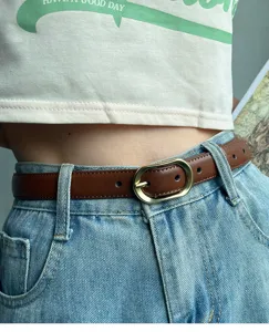 Women brown leather belt detail shot, slim waist strap with gold oval buckle for jeans.