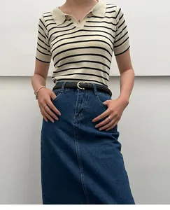 Detailed shot of a stylish thin black leather belt worn with casual striped top and denim skirt.
