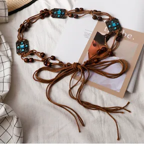 Detail view of bohemian waist chain featuring brown rope, wooden beads and vintage buckles.