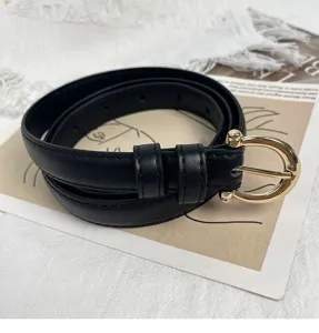 Dettaglio di una cintura in pelle nera classica con una fibbia ad ardiglione dorata.