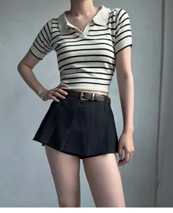 Women's minimalist short sleeve striped polo top with brown leather belt and pleated skirt.