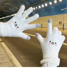 Close-up detail of cute white knitted winter touch screen gloves with adorable bear embroidery.
