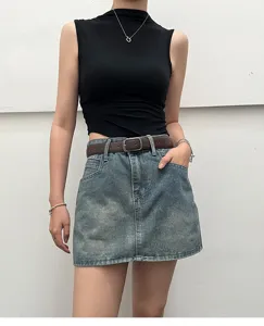Detailed shot of a stylish women's brown leather belt paired with a casual denim skirt.