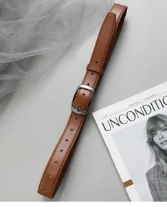 Close-up detail of brown leather belt with stylish metal buckle on clean minimal surface.