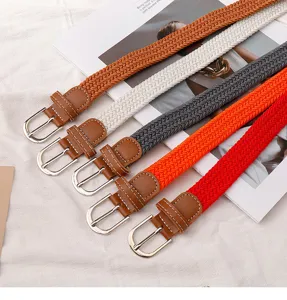 Close-up detail of colorful woven elastic belts with brown PU leather tips and metal buckles.