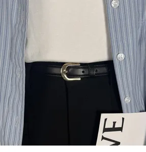 Minimalist black leather belt detail shot with gold buckle, casual fashion waist accessory.