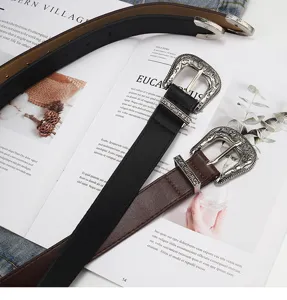 Detailed shot of retro western style leather belts with intricate metal carved buckles.