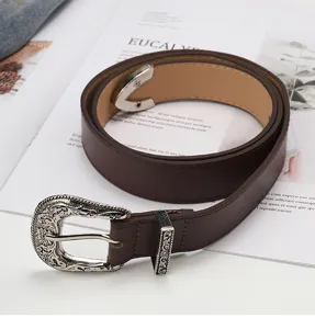 Detailed close-up of a vintage brown leather belt featuring an intricate engraved silver buckle.