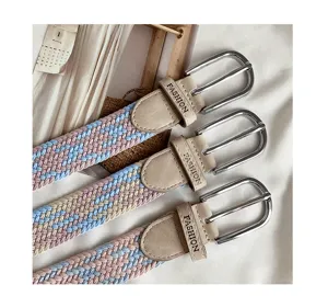 Detailed view of women's woven elastic belt with silver buckle and stylish patterned design.