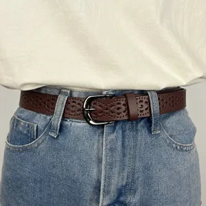 Women's brown hollow-out leather belt with metal buckle, stylish jeans waist accessory.