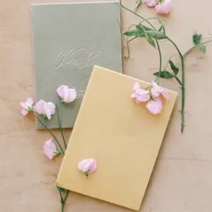 Velvet wedding vow books set, elegant pink floral decor, green and yellow keepsake notebooks for ceremony.