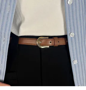 Detail view of a stylish slim brown leather belt with a classic gold buckle, perfect for jeans.