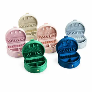 Portable round velvet jewelry storage box with multiple colors and ring slots for travel.