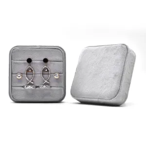 Gray velvet jewelry box with matching earrings and rings set displayed neatly on white bg.