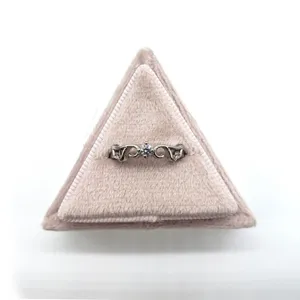 Bague en argent élégante présentée sur une boîte à bijoux triangulaire en velours rose.