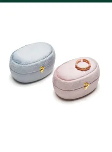 Detail shot of elegant oval velvet ring jewelry storage boxes in blue and pink with gold clasps.