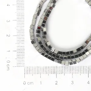 Detailed close-up of 2mm hematite square beads on a ruler grid for size reference, DIY jewelry.