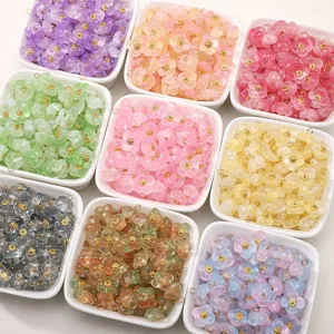 Nahaufnahme von bunten Glasblumen-Charms mit goldenen Schlaufen für DIY Schmuckherstellung.
