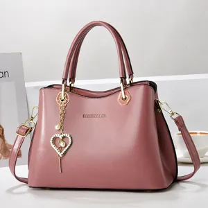 Pink shoulder bag detail, elegant design with gold hardware, heart pearl pendant decor.