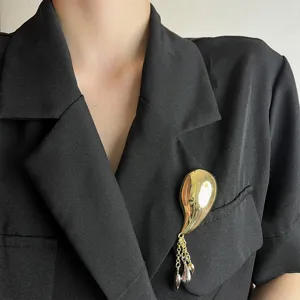 Detailed close-up of a French retro metal streamlined chili brooch with delicate tassel pendants.
