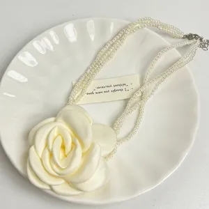 Close-up detail van multi-layer parelketting met grote stoffen bloemhanger, elegante sieraden.