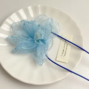 Blue organza flower detail choker necklace ribbon wristband accessory on white plate close up