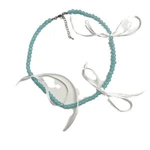 Close-up detail van de lichtblauwe kraal choker ketting met stijlvolle elegante witte strikken.