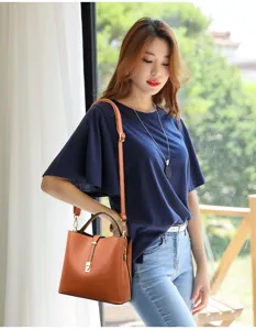 Detail shot of stylish brown PU leather shoulder bag worn by model near window scene.