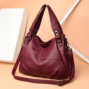 Burgundy women's leather shoulder bag detail shot, showing textured surface, hardware, and strap.