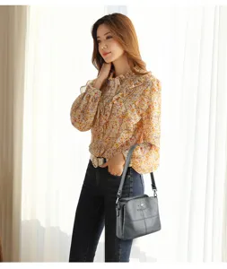 Nahaufnahme der eleganten grauen Ledertasche an Model in modernem Innenbereich stilvoll.