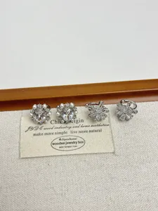 Primer plano de exquisitios clips de oreja plateados con circonitas y perlas, diseño floral.