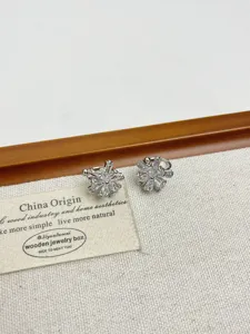 Primer plano detallado de pendientes clip de sol en circón con piedras brillantes en acabado plateado.