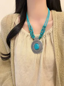 Primo piano dettaglio della collana boho in turchese, ciondolo argento vintage elegante.