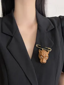 Close-up detail of retro enamel leopard head brooch on black blazer, stylish fashion accessory.