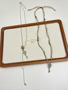 Vista dettagliata di collana con pendente a chiave stile vintage e catena di maglione intrecciata.