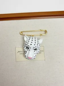 Detailed shot of retro white enamel leopard head brooch pin, vintage jewelry accessory.